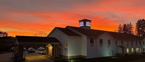 A motel with a prominent 'The Inn' sign on the roof, a covered parking area, and a well-lit driveway.