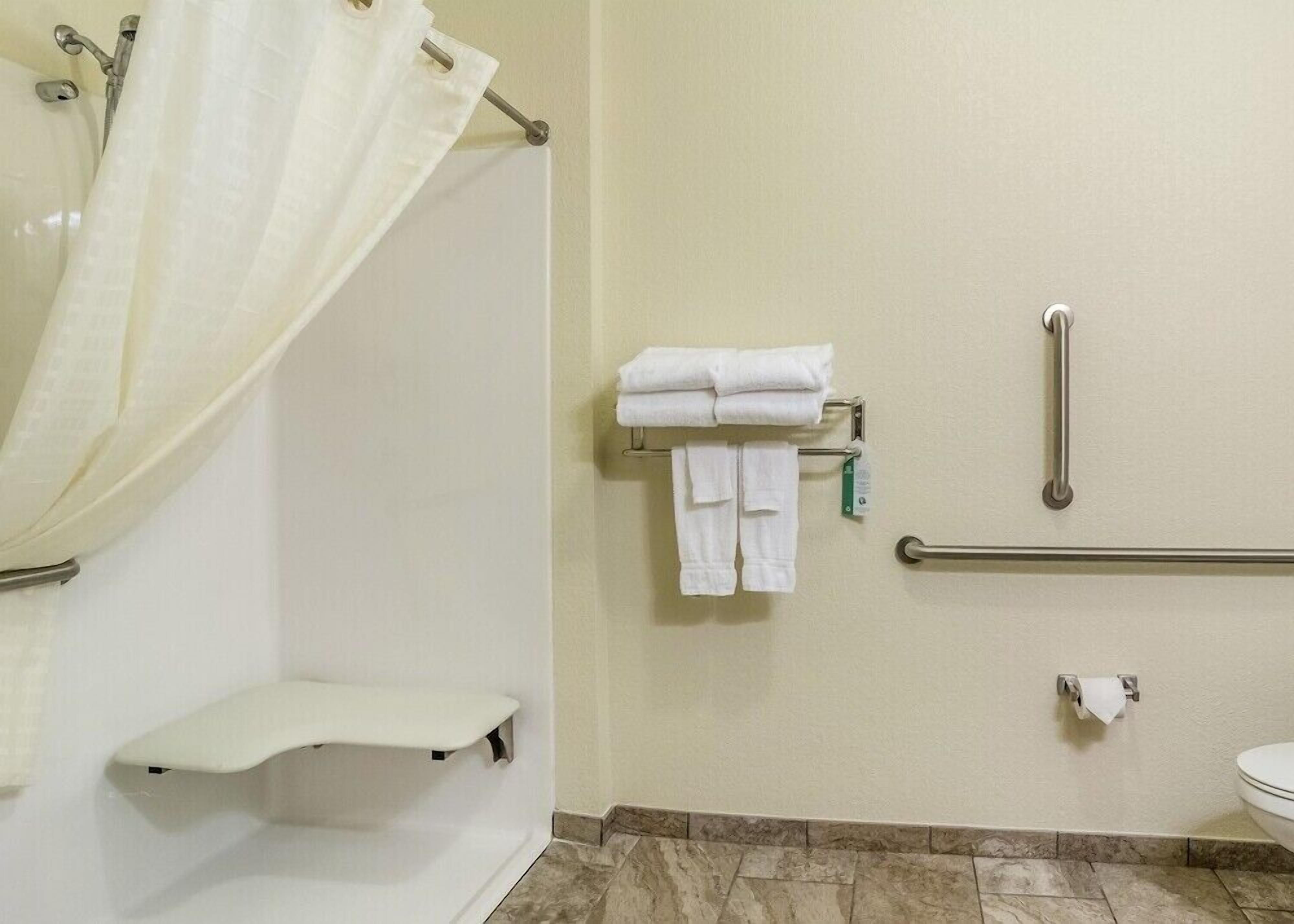Un baño con ducha, inodoro y barra de apoyo.
