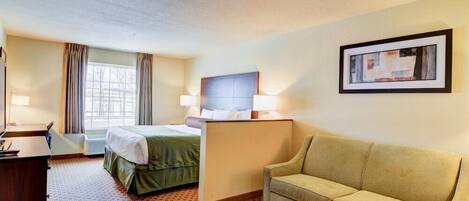 A hotel room with a bed, a desk, a couch, and a framed picture on the wall.