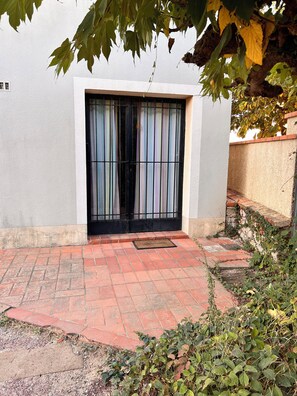 A building entrance with a black metal gate, a red brick pathway, and a white wall. - Ground-floor apartment in a villa overlooking the beach (Valras-Plage)