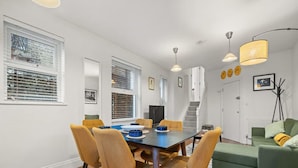 A dining area with a table, chairs, and a staircase leading to another level. - Brand-new Fulham Stay Near Thames (London)