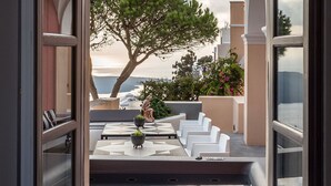 Un balcone aperto con vista sul mare, un albero e un'area salotto esterna.