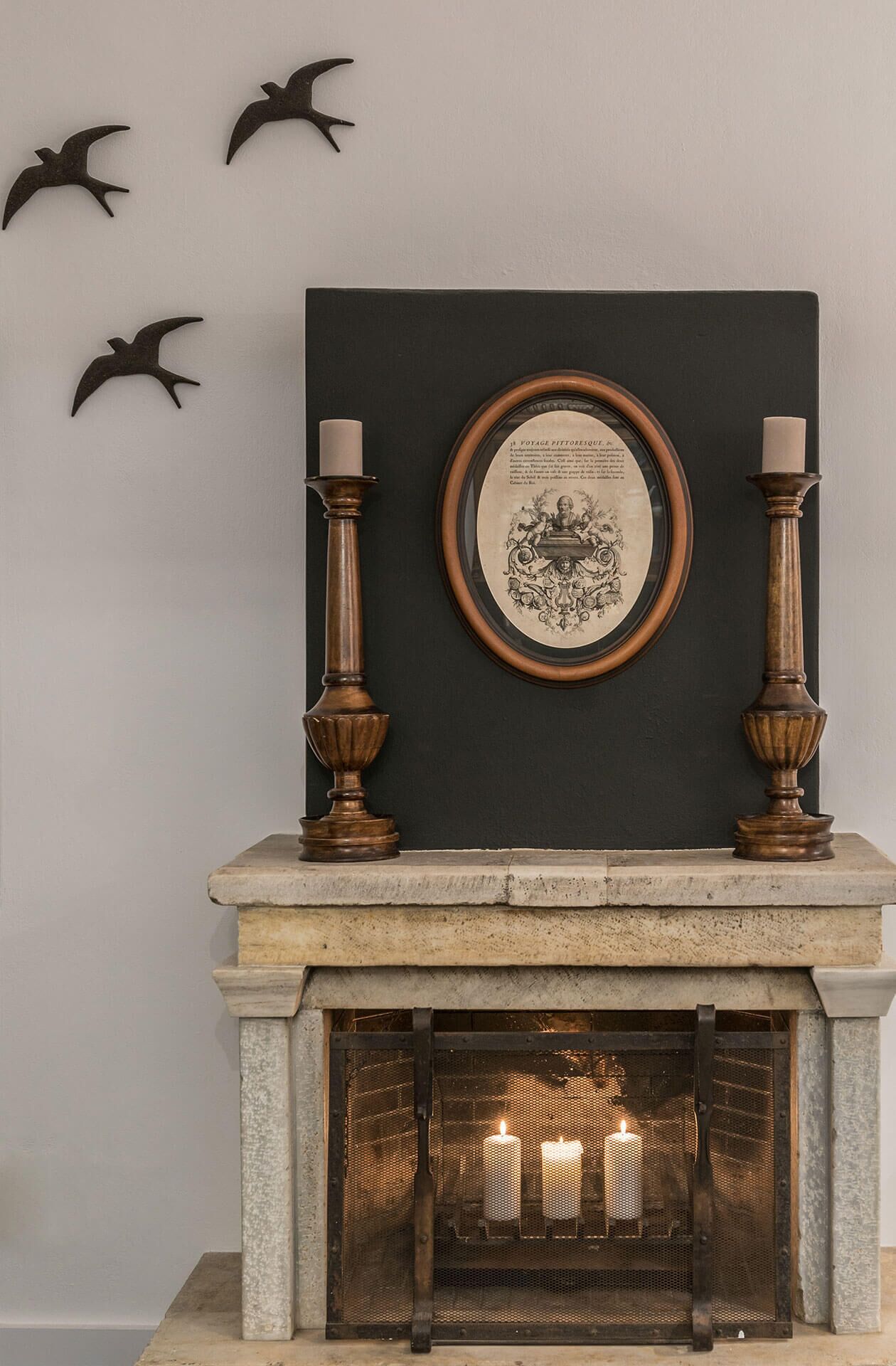 Una chimenea con una placa enmarcada sobre ella, flanqueada por dos candelabros.