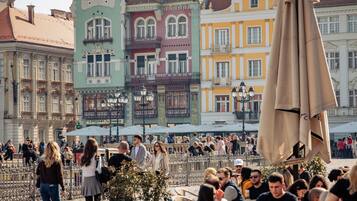 Uma praça de paralelepípedos com edifícios históricos, mesas ao ar livre e um suporte para bicicletas.