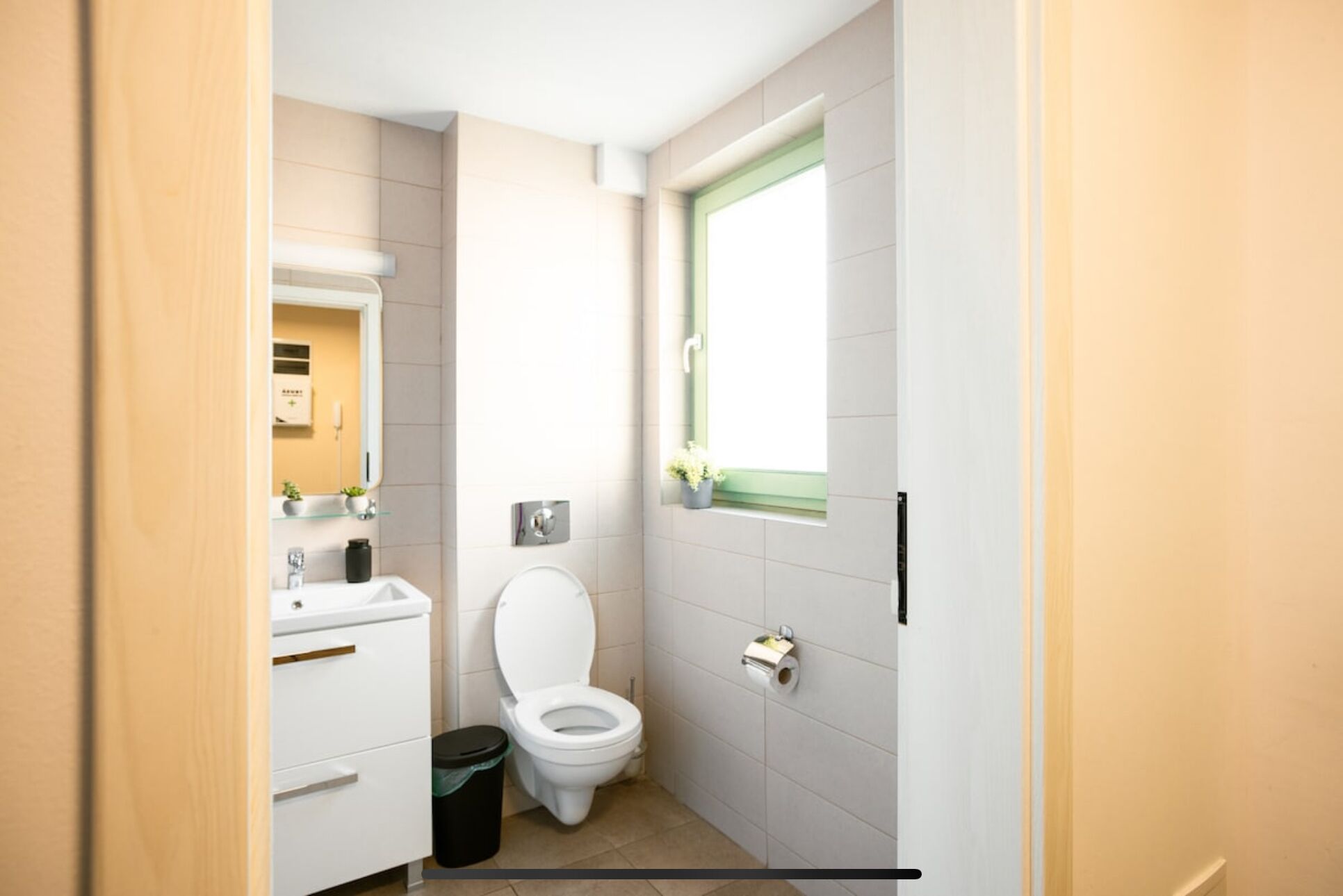 Un baño pequeño y moderno con inodoro, lavamanos y espejo.