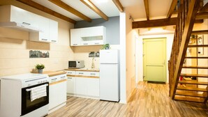 A modern kitchen with white cabinets, a microwave, a refrigerator, and an oven. There is a wooden staircase leading to a green door. - 1st Nest in Heart of Timisoara (Timisoara)