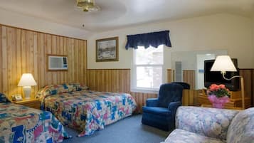 A hotel room with two beds, a sofa, a chair, a TV, a lamp, and a window with a view.