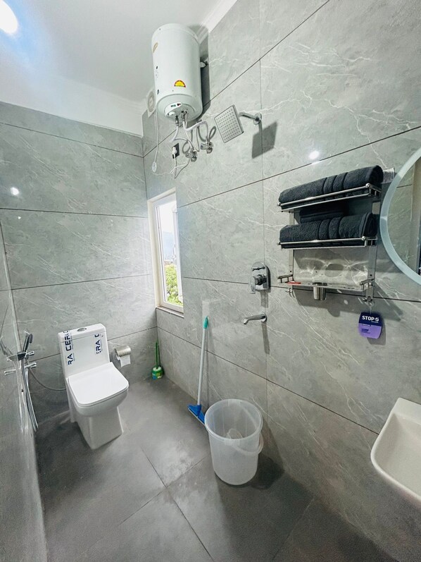 Une salle de bain moderne équipée de toilettes, d’un bidet, d’un porte-serviettes et d’un espace douche.