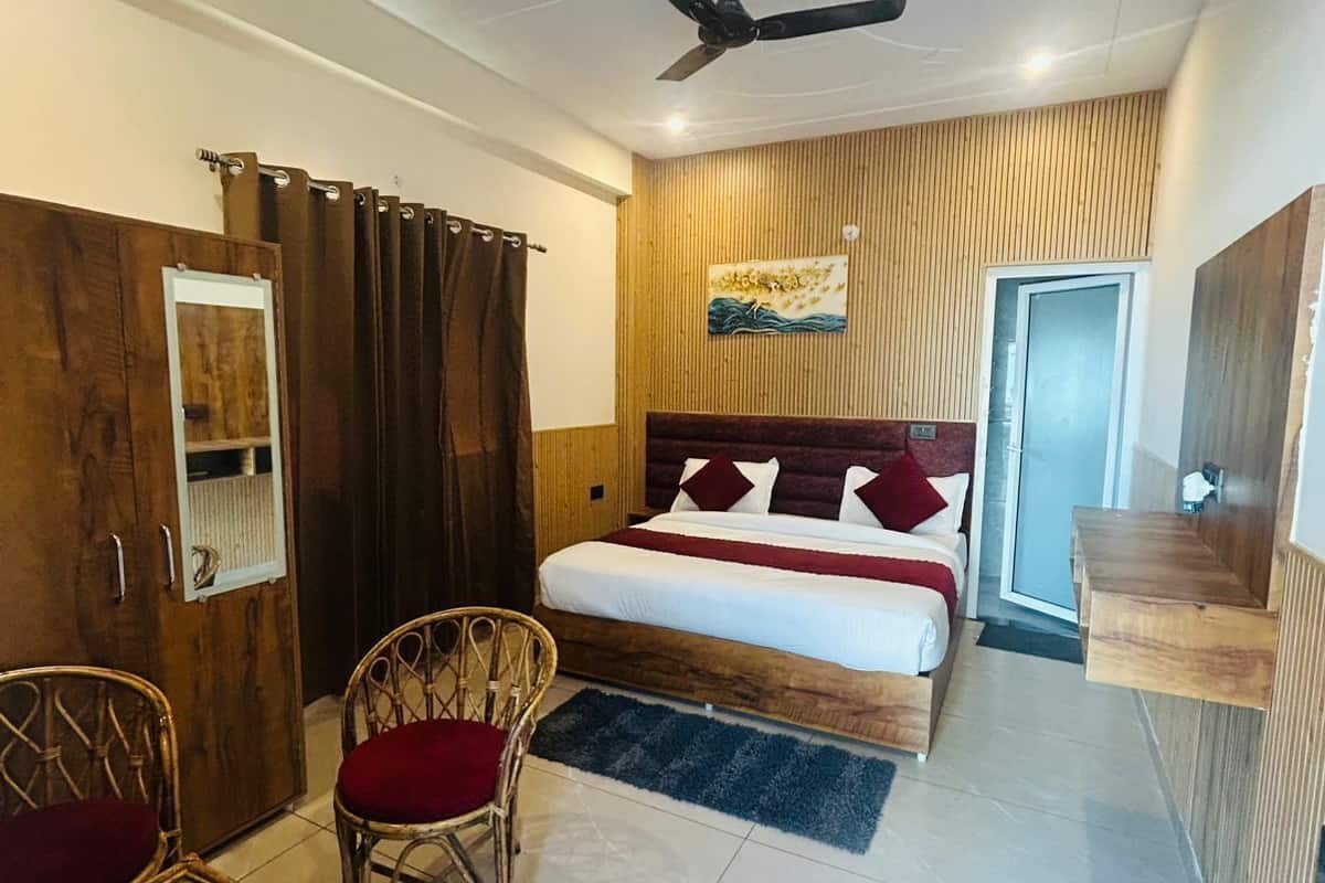 A bedroom with a bed, a ceiling fan, a wooden wardrobe, a mirror, and a door.