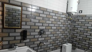 A bathroom with a white sink, a toilet, and a shower. The walls are tiled with a patterned design. - La Casa Bonita (Rishikesh)