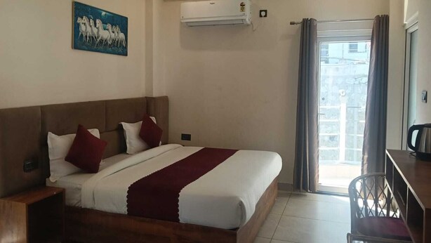 A hotel room with a bed, a desk, and a window. - La Casa Bonita (Rishikesh)