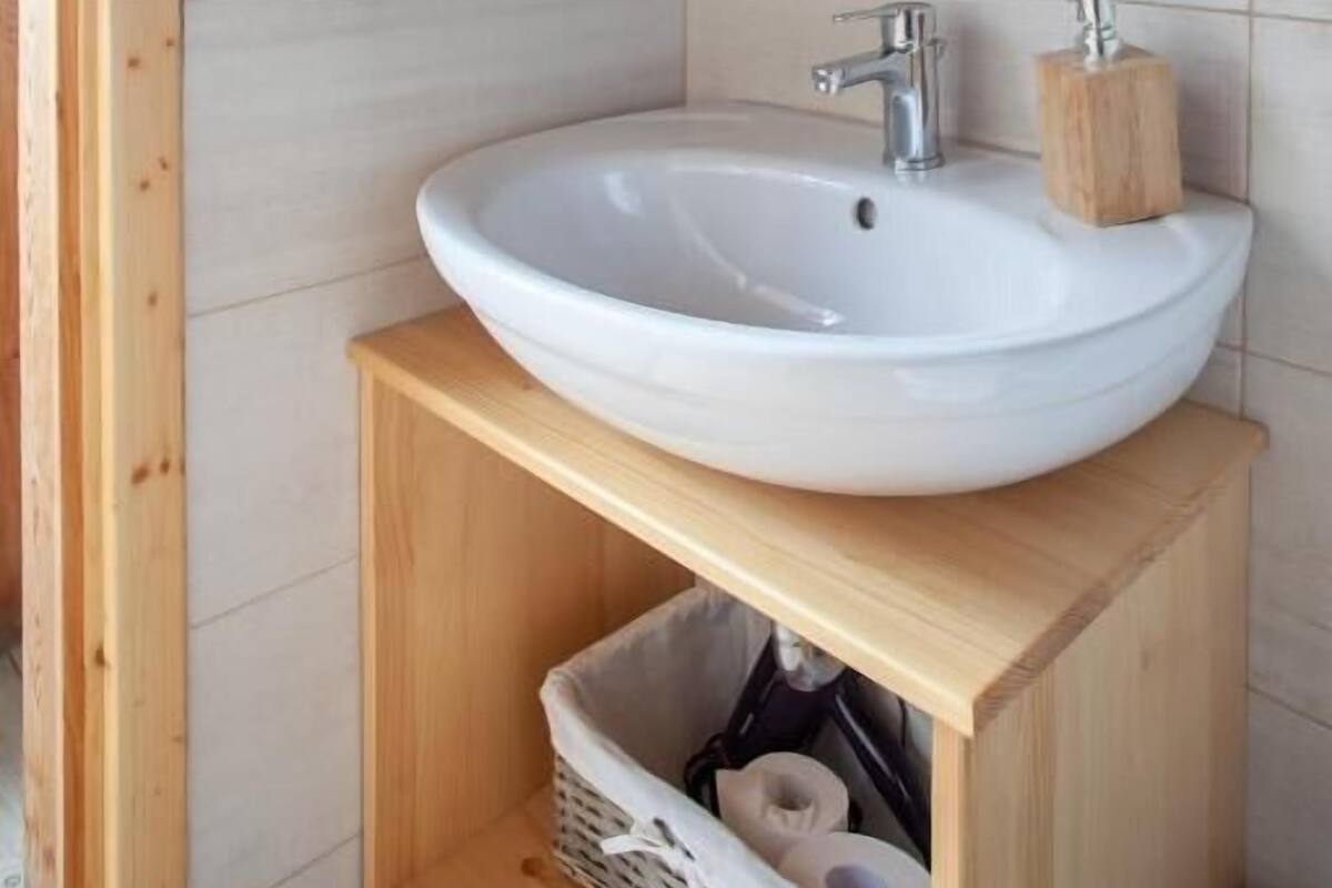 Un baño con tocador de madera, lavabo blanco y espejo encima.