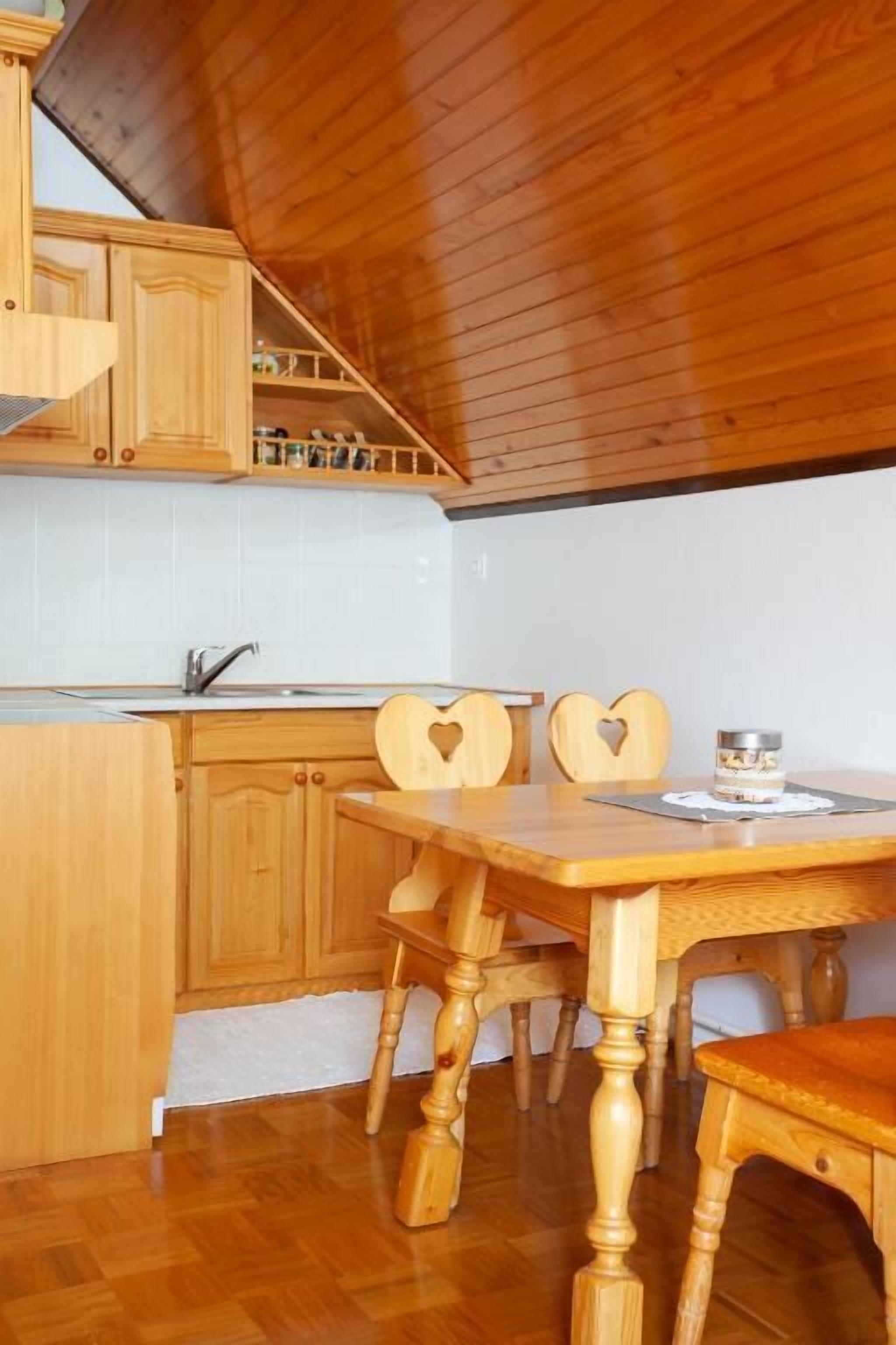 A wooden kitchen with a dining table and chairs.