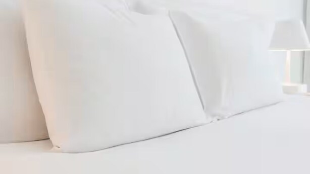 Un lit bien fait, avec du linge de lit et des oreillers blancs.