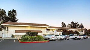 Un motel avec un parking et plusieurs voitures garées.