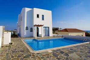 Un bâtiment moderne, de couleur blanche, doté d’une piscine et d’un revêtement de sol en pierre.
