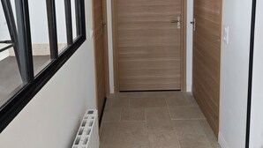 A hallway with a wooden door, a radiator, and a window. - Large apartment between Paris - Disneyland - CDG Airport - B.Olympique Vaires (Brou-sur-Chantereine)