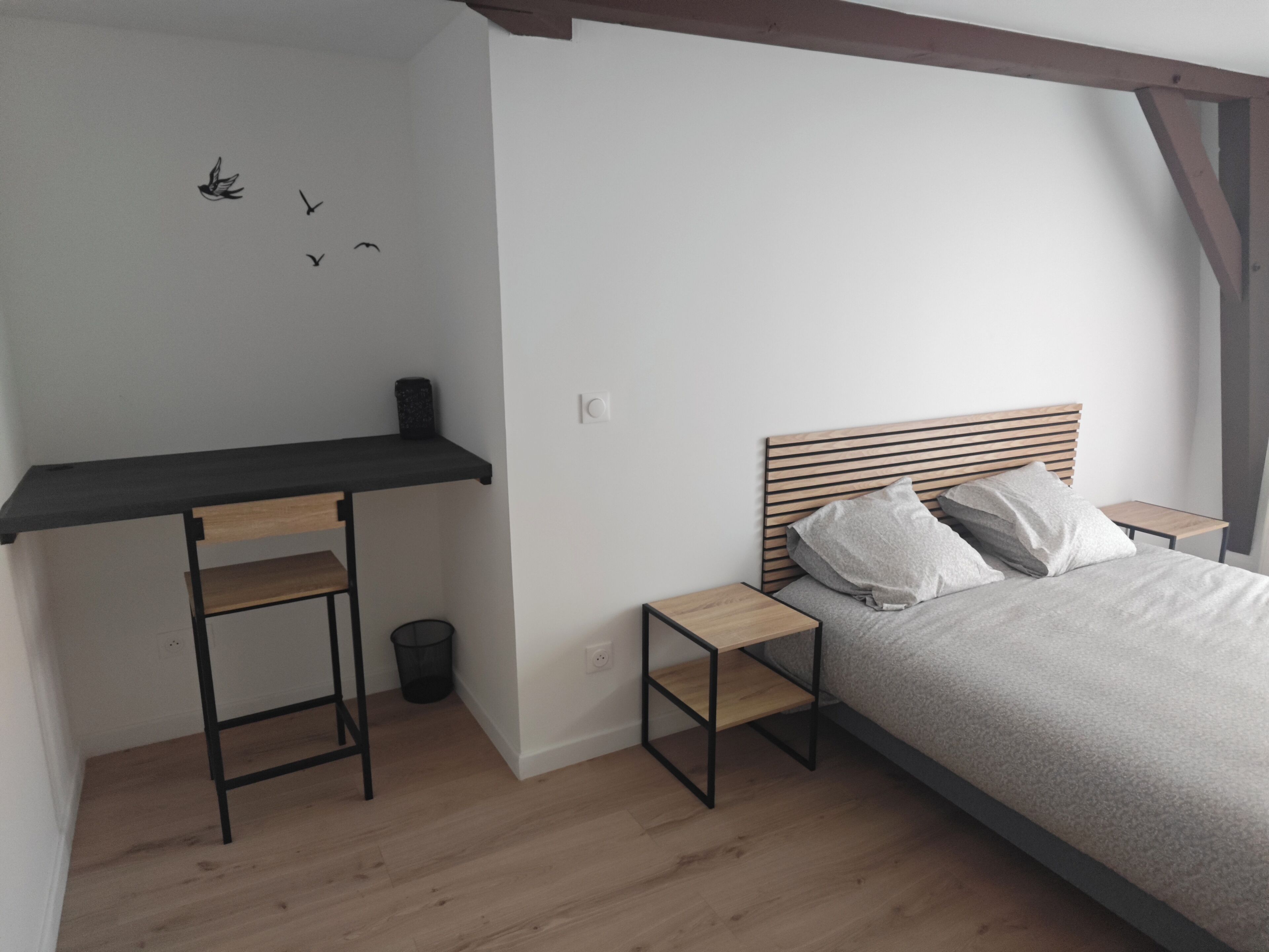 A bedroom with a bed, a nightstand, a desk, and a chair.