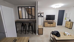 A modern living room with a dining area, a TV, and a staircase leading to an upper level. - Large apartment between Paris - Disneyland - CDG Airport - B.Olympique Vaires (Brou-sur-Chantereine)