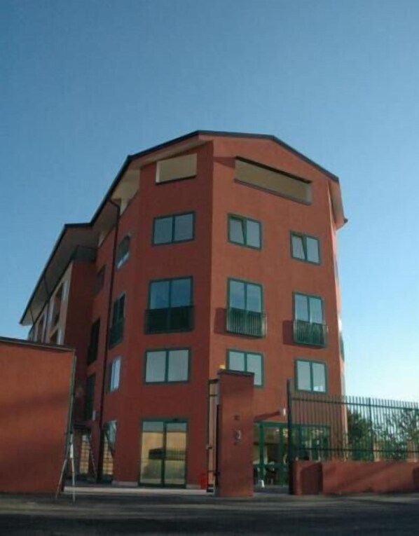 A multi-story building with a red facade, large windows, and a gated entrance. - Hotel HMR Rho Milano (Rho)