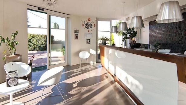 Un área de recepción moderna con puerta de cristal que da al exterior, un mostrador de recepción y un espacio de espera con sillas blancas.