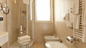 Un baño moderno con ducha envuelta en vidrio, un lavamanos, un bidé y un perchero para toallas.