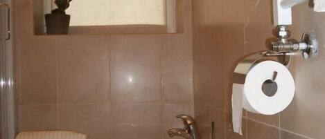 A bathroom with a toilet, sink, and window.
