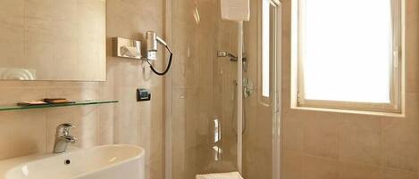 A modern bathroom with a glass-enclosed shower, a sink, a vanity, and a window providing natural light.