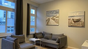A living room with a grey sofa, a white side table, and two paintings on the wall.