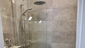 A modern bathroom with a glass-enclosed shower, a toilet, and a sink.