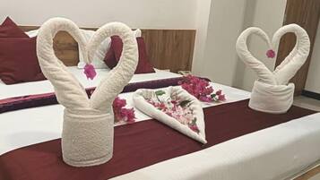 Habitación de hotel con una cama, almohadas y una decoración de toallas con forma de cisnes y flores.