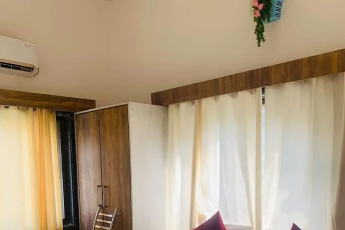 A hotel room with a large bed, a desk, a chair, and a window with curtains.