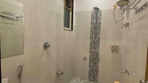 A bathroom with a tiled floor, a sink, a toilet, and a shower area. - Leopard Valley Resort (Kumbhalgarh)