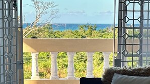 Ein Balkon mit Meerblick, ein Bett mit Felldecke und ein Fliesenboden.