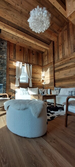 Ein gemütliches Zimmer mit rundem Pouf, einer Couch, einer Holzzahl und einer Steinwand.