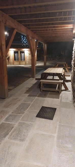 An outdoor wooden pavilion with picnic tables and a stone floor. - L'Échappée Chalet sauna 7 bdrms terraces sublime view skiroom close to cable car (Champagny-en-Vanoise)