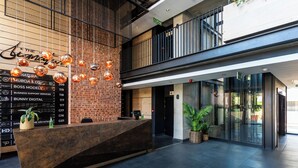 A modern reception area with a brick wall, a wooden reception desk, and hanging spherical lights. - Harbourline Haven | Signature #304 | De Waterkant (Cape Town)