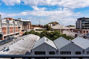 Eine Stadtansicht mit verschiedenen Gebäuden, darunter eine Mischung aus moderner und älterer Architektur, und einem klaren Himmel mit vereinzelten Wolken.