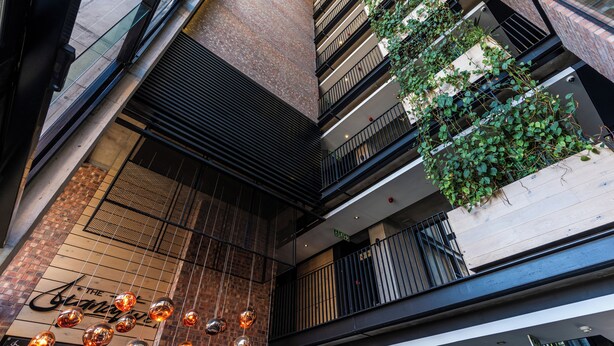 A multi-level atrium with a glass ceiling, metal railings, and greenery on balconies. - Harbourline Haven | Signature #304 | De Waterkant (Cape Town)