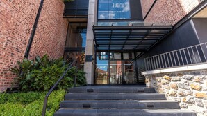 A modern building with a brick facade, a glass entrance, and a stone wall. - Harbourline Haven | Signature #304 | De Waterkant (Cape Town)