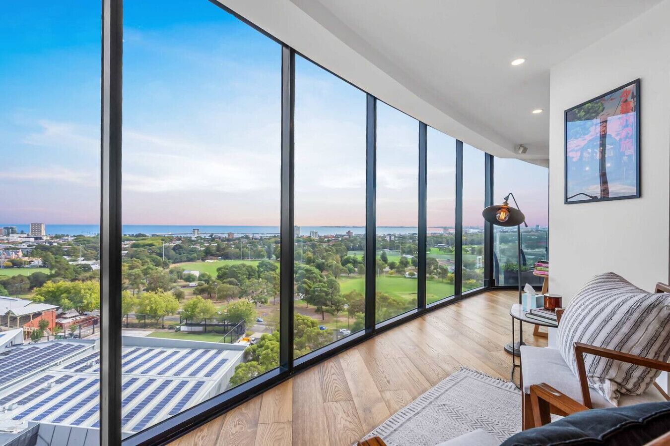 Ein geräumiges Zimmer mit großen Fenstern und Blick auf Stadt und Grünflächen.