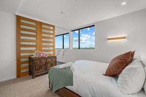 A bedroom with a bed, a dresser, a window with a view, and a wooden partition. - City and Lake Views with Balcony Pool and Parking (Melbourne)