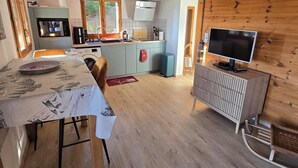 A compact living space with a dining area, kitchenette, and a television. - 37 m2 apartment in RDC chalet with south-facing lake view (Puy-Sanières)
