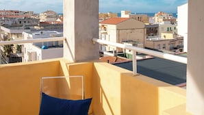 En balkon med blåt betræk, frit udsyn over bybilledet, og en bygning med rødt tag.