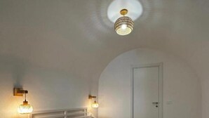 A bedroom with a bed, two bedside tables, a chair, a door, and a ceiling light fixture. - Domo Masial - Alghero (Alghero)
