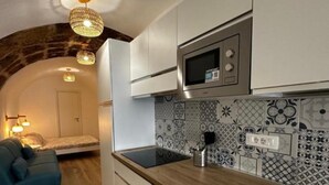 A modern kitchen with a microwave, sink, and patterned backsplash. There is a wooden countertop and a blue sofa in the adjacent living area. - Domo Masial - Alghero (Alghero)