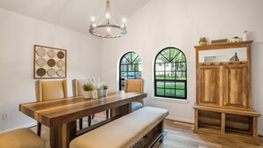 A dining area with a wooden table, cushioned benches, and a chandelier.
