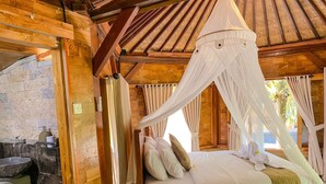 A wooden room with a bed under a canopy, a stone sink, and a window with curtains. - Wimala Farm House (Munduk)