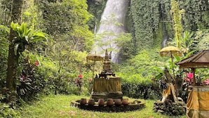 A lush garden with a waterfall, a pagoda-style structure, and a statue. - Wimala Farm House (Munduk)