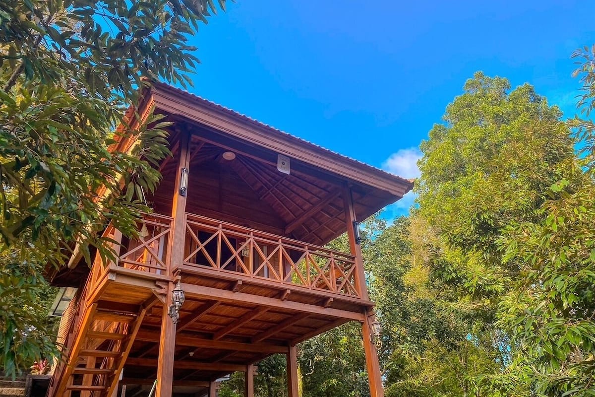 A wooden structure with a balcony, surrounded by trees.